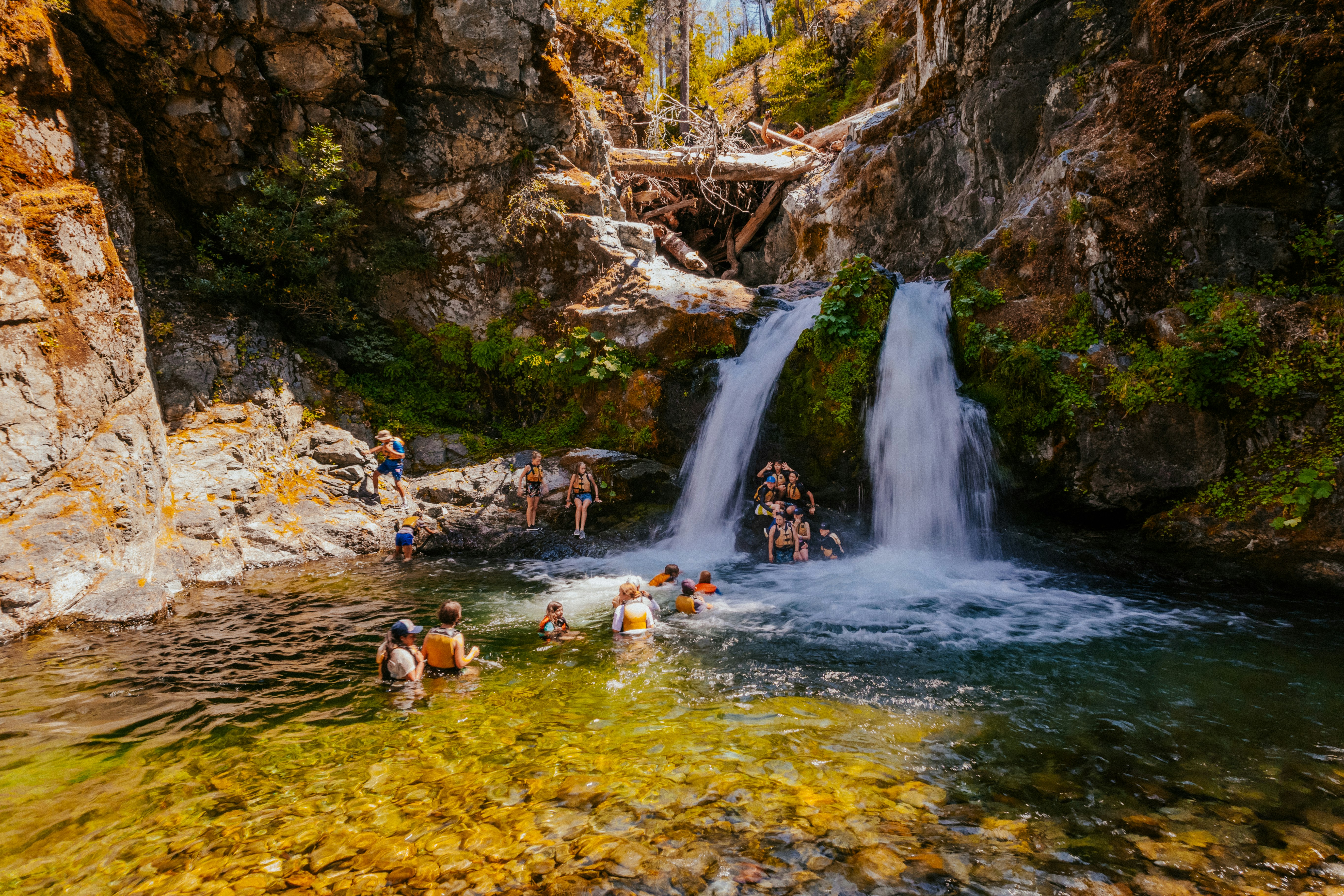 people in water falls during daytime